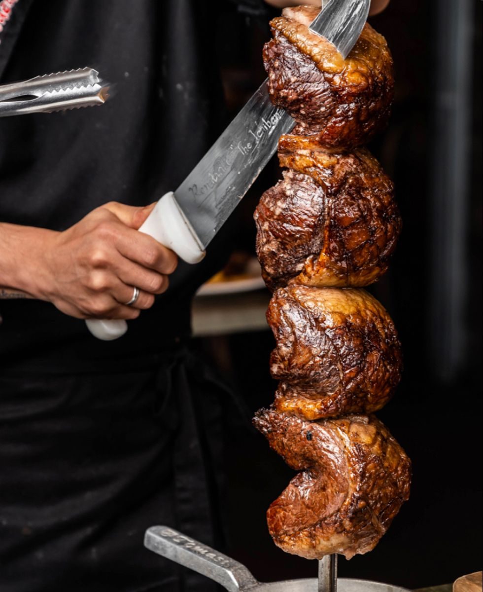 Churrasqueiro cortando picanha no espeto